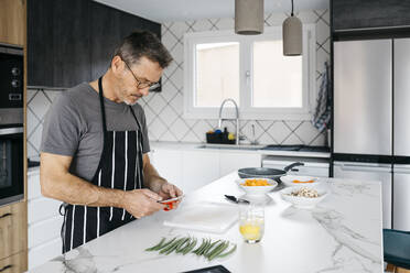 Man using smart phone at kitchen island - JRFF05235