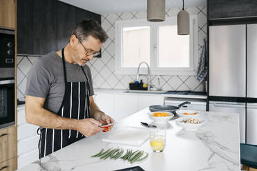 Mann benutzt Smartphone an Kücheninsel - JRFF05235