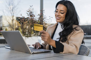 Lächelnde Geschäftsfrau mit Kreditkarte beim Online-Shopping am Laptop - JRVF02423