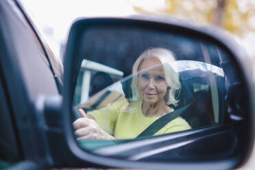 Ältere Frau im Ruhestand, die Auto fährt und sich im Seitenspiegel spiegelt - AMWF00066