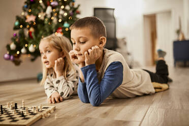 Bruder und Schwester liegen zusammen in der Nähe des Schachbretts zu Hause - ZEDF04364