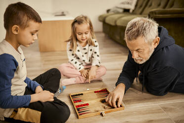 Mann spielt Backgammon mit Enkelkindern zu Hause - ZEDF04369
