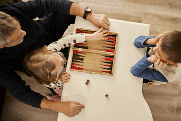 Großvater spielt Backgammon am Tisch mit Enkeln zu Hause - ZEDF04377