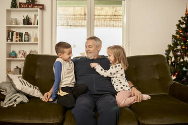 Junge und Mädchen sitzen mit ihrem Großvater auf dem Sofa zu Hause - ZEDF04385