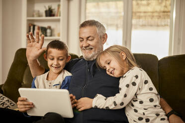 Enkelkinder nutzen Tablet-PC mit Großvater zu Hause - ZEDF04388