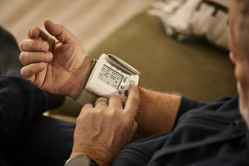 Senior man checking blood pressure at home - ZEDF04408