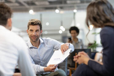 Businessman discussing document with colleagues in office - EIF02918