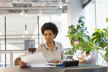 Geschäftsfrau mit Papierdokument bei der Arbeit am Tisch im Büro - EIF02921