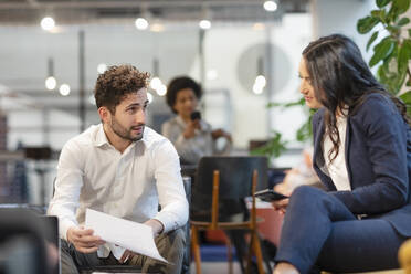 Businessman discussing document with colleague at office - EIF02938