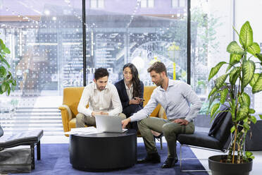 Businessman with laptop discussing with colleagues at office - EIF02939