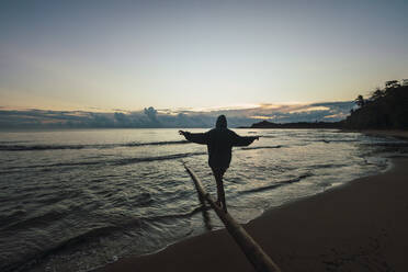 Carefree woman walking on log at beach, Limon, Costa Rica - RSGF00802