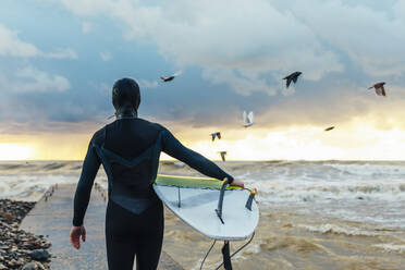 Surfer geht mit Surfbrett auf dem Pier Richtung Meer - OMIF00416