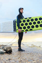 Selbstbewusster Surfer mit Surfbrett auf dem Pier stehend - OMIF00419