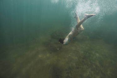 Frau schwimmt im Urlaub unter Wasser - RSGF00804