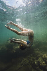 Unbekümmerte junge Frau, die unter Wasser flippt - RSGF00806