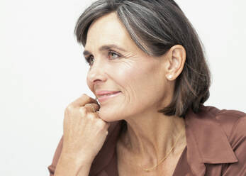 Thoughtful woman with hand on chin against white background - JBYF00086