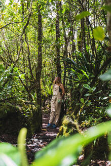 Frau inmitten von Bäumen bei der Erkundung des Waldes im Arenal Volcano National Park, La Fortuna, Provinz Alajuela, Costa Rica - RSGF00816