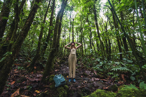 Junge Frau inmitten von Bäumen beim Wandern im Arenal Volcano National Park, La Fortuna, Provinz Alajuela, Costa Rica - RSGF00819