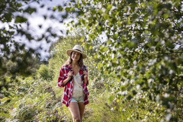 Woman standing in forest at Cannock Chase on sunny day - WPEF05652