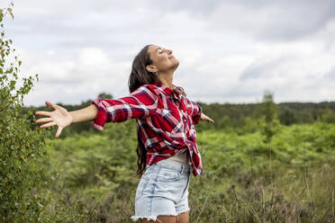 Happy woman standing with arms outstretched at Cannock Chase - WPEF05661