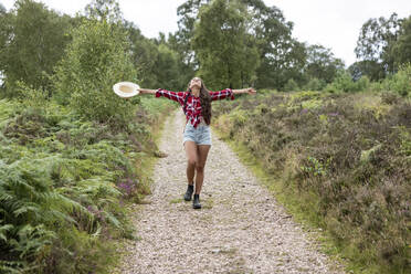 Frau mit Hut auf dem Fußweg inmitten von Pflanzen in Cannock Chase - WPEF05668