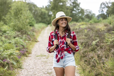 Smiling woman with hat walking on footpath at Cannock Chase - WPEF05669
