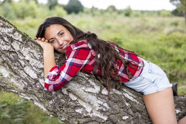 Smiling woman lying on branch at Cannock Chase - WPEF05671