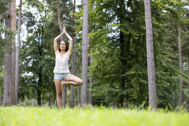 Frau mit verschränkten Händen beim Yoga in der Baumstellung in Cannock Chase - WPEF05683