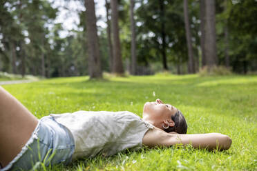 Frau mit geschlossenen Augen, die sich im Gras in Cannock Chase entspannt - WPEF05689