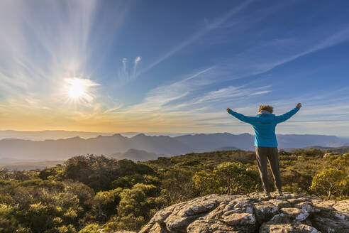 Australien, Victoria, Weibliche Touristin steht mit erhobenen Armen auf dem Gipfel des Mount William bei Sonnenuntergang - FOF12631