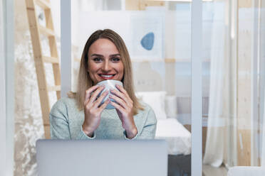 Lächelnde Geschäftsfrau mit Kaffeetasse im Studio - PNAF02776