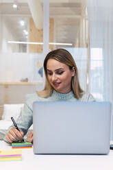 Businesswoman working at desk in studio - PNAF02780