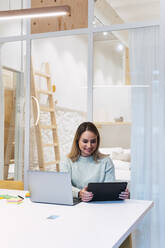 Businesswoman using tablet PC by laptop at studio - PNAF02784