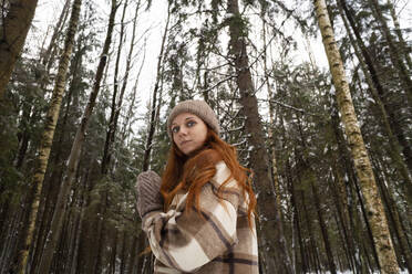 Confident redhead woman in front of trees in forest - SSGF00392
