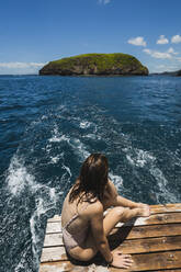 Junge Frau schaut auf eine Insel, die auf einem Boot im Meer sitzt, Strand Del Coco, Provinz Guanacaste, Costa Rica - RSGF00827