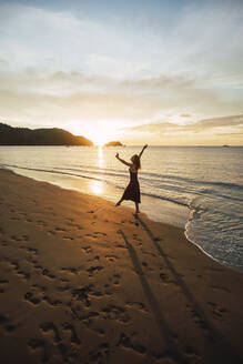 Frau tanzt bei Sonnenuntergang am Strand Del Coco, Provinz Guanacaste, Costa Rica - RSGF00829