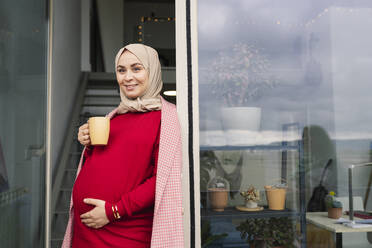 Nachdenkliche Frau mit Kaffeetasse vor der Tür - JCCMF05092