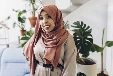 Lächelnde Frau mit Hidschab im Wohnzimmer - JCCMF05109