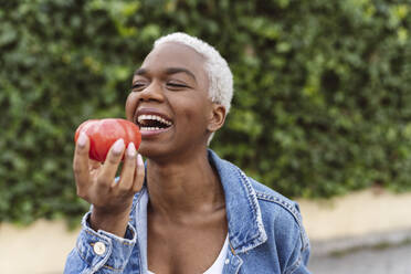 Young woman laughing holding tomato in hand - JCCMF05125