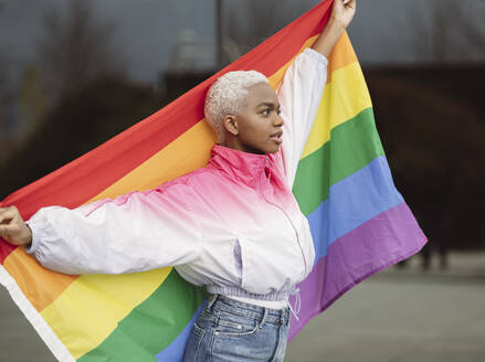 Confident LGBTQIA woman holding rainbow flag - JCCMF05142