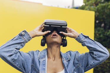 Frau mit Virtual-Reality-Headset vor einer gelben Wand - JCCMF05151