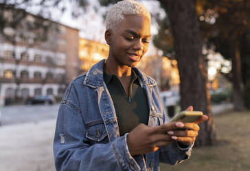 Frau benutzt Smartphone bei Sonnenuntergang - JCCMF05179