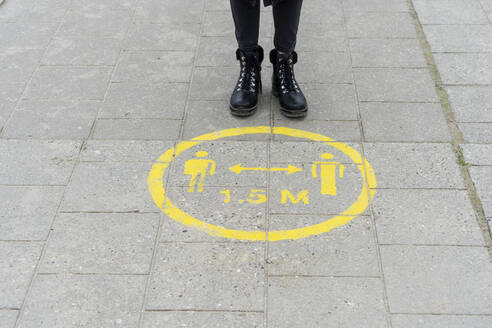 Woman standing near social distance marking on pavement - CHPF00823