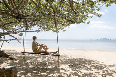 Frau sitzt auf einer Schaukel am Strand von Ao Nang, Provinz Krabi, Thailand - CHPF00825