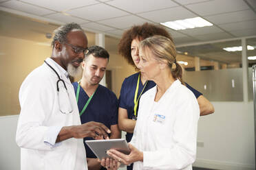 Male doctor explaining colleagues over tablet PC in medical room - PMF02149