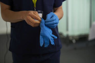 Krankenschwester mit chirurgischen Handschuhen in einem medizinischen Raum - PMF02154