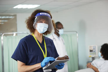 Nurse with face shield using tablet PC in medical room - PMF02157