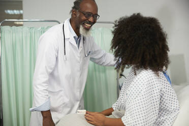 Zufriedener Arzt betrachtet Patient mit Oximeter im Krankenhaus - PMF02169