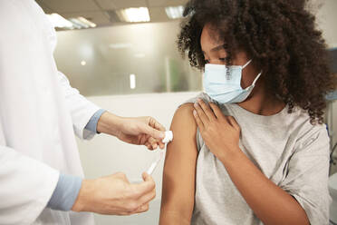 Mädchen mit Schutzmaske bei der COVID-19-Impfung im Krankenhaus - PMF02211