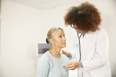 Arzt untersucht Patient mit Stethoskop in medizinischem Raum - PMF02223